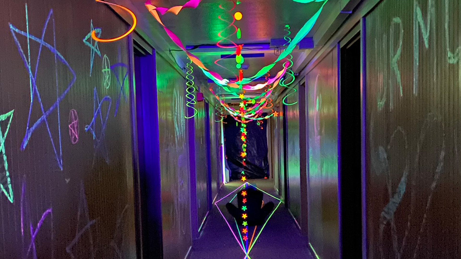 A dark hallway with glowing ribbons and stars drawn on the walls