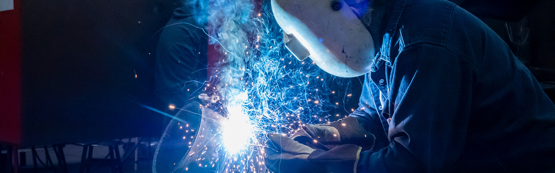 A welder in a hood with sparks flying